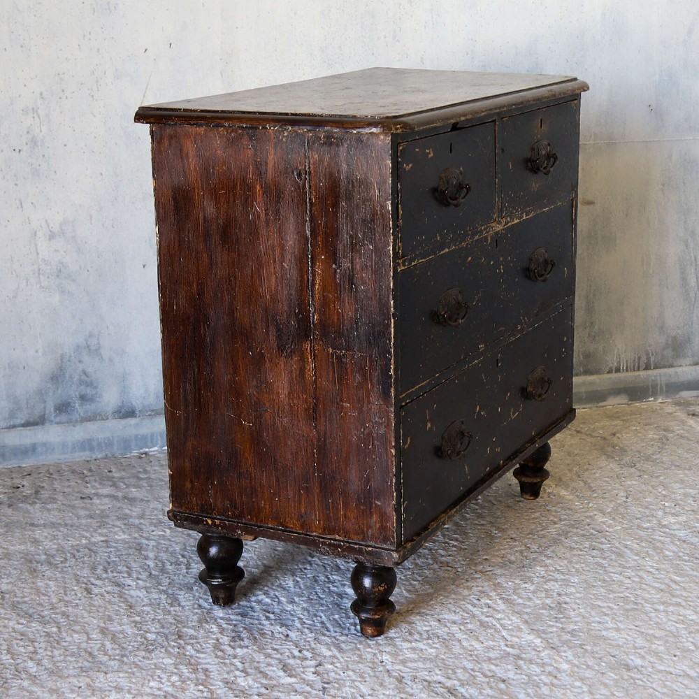 An antique pine chest of drawers featuring a dark brown scumble paint finish, Art Nouveau brass drop handles, two short drawers over two long drawers, and turned feet. View VI