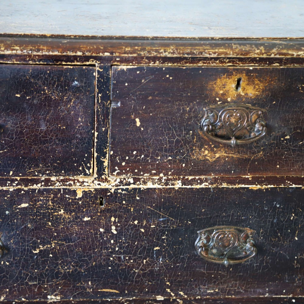 An antique pine chest of drawers featuring a dark brown scumble paint finish, Art Nouveau brass drop handles, two short drawers over two long drawers, and turned feet. View X