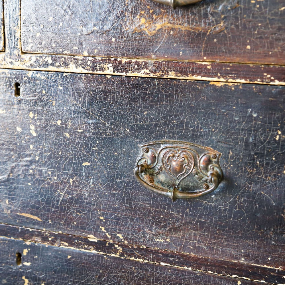 An antique pine chest of drawers featuring a dark brown scumble paint finish, Art Nouveau brass drop handles, two short drawers over two long drawers, and turned feet. View XII
