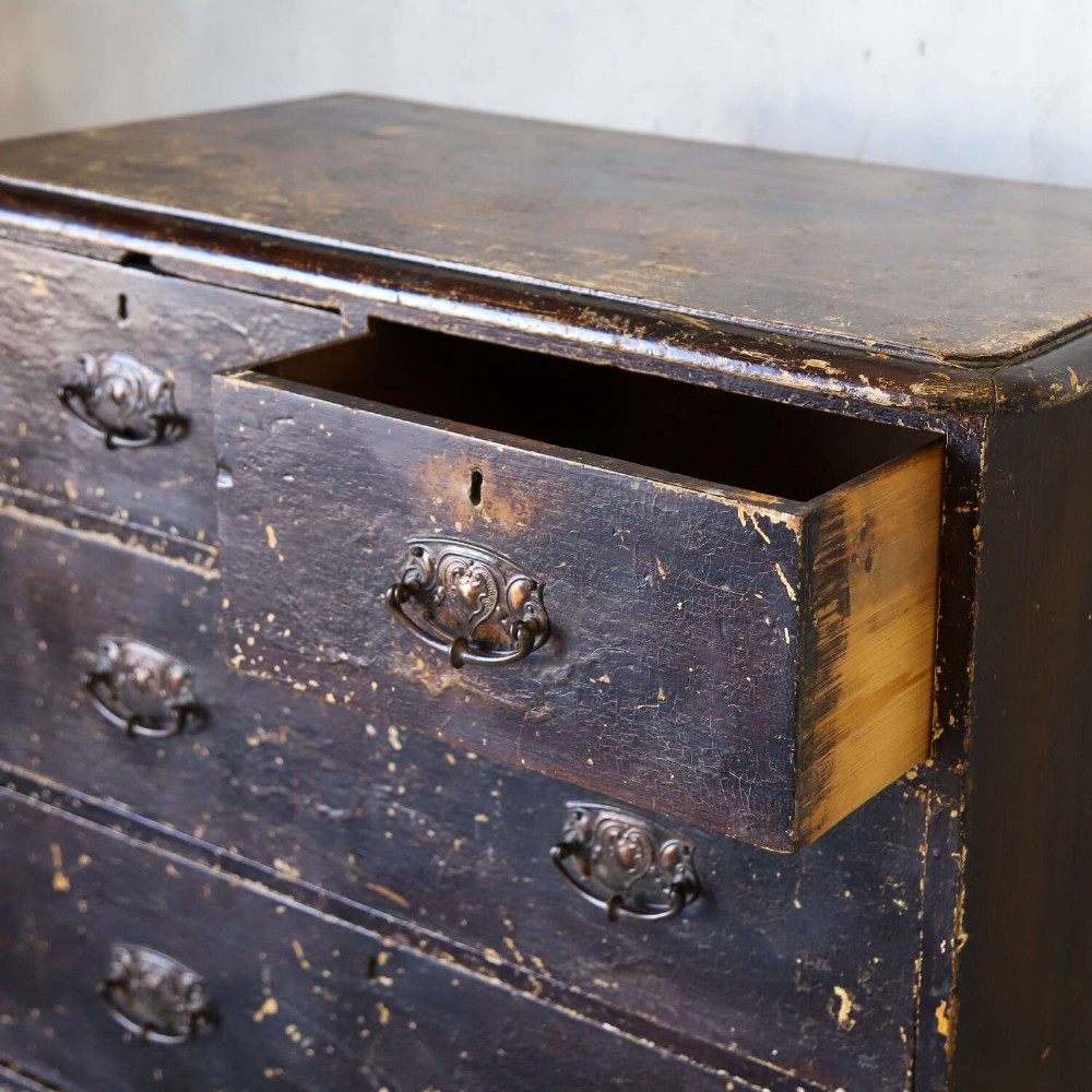 An antique pine chest of drawers featuring a dark brown scumble paint finish, Art Nouveau brass drop handles, two short drawers over two long drawers, and turned feet. View XIII