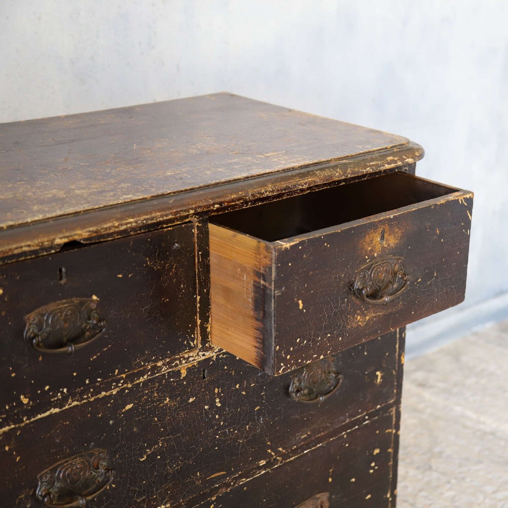 An antique pine chest of drawers featuring a dark brown scumble paint finish, Art Nouveau brass drop handles, two short drawers over two long drawers, and turned feet. View XIV