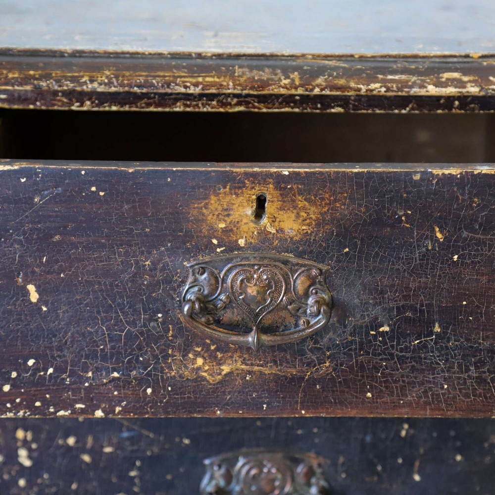 An antique pine chest of drawers featuring a dark brown scumble paint finish, Art Nouveau brass drop handles, two short drawers over two long drawers, and turned feet. View XV