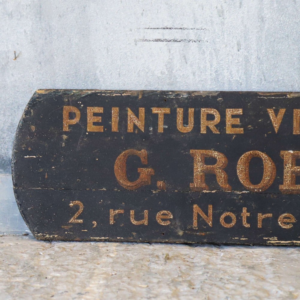 A rectangular black painted timber trade sign featuring gold hand-painted French text reading Peinture Vitrerie Decors G. Robillard Arras. View III