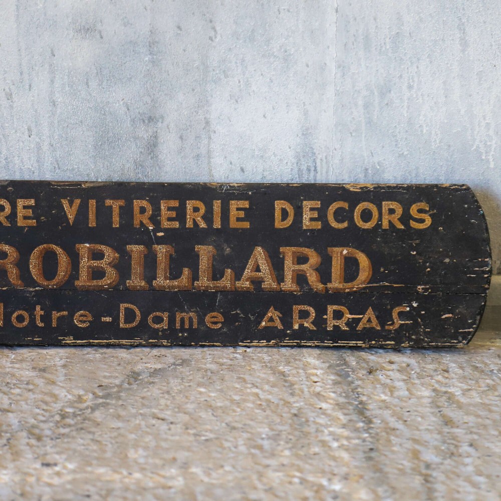 A rectangular black painted timber trade sign featuring gold hand-painted French text reading Peinture Vitrerie Decors G. Robillard Arras. View IV