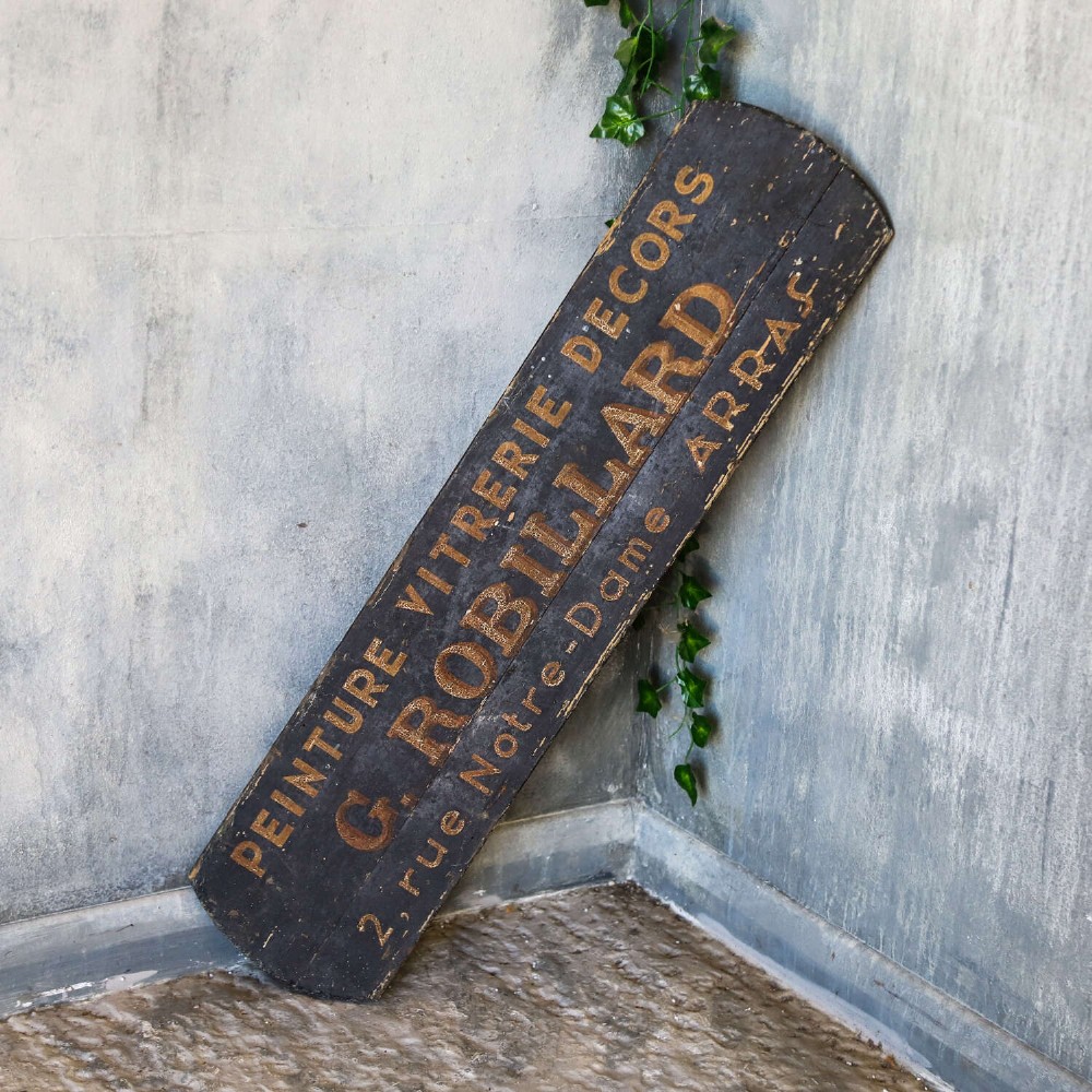 A rectangular black painted timber trade sign featuring gold hand-painted French text reading Peinture Vitrerie Decors G. Robillard Arras. View VI