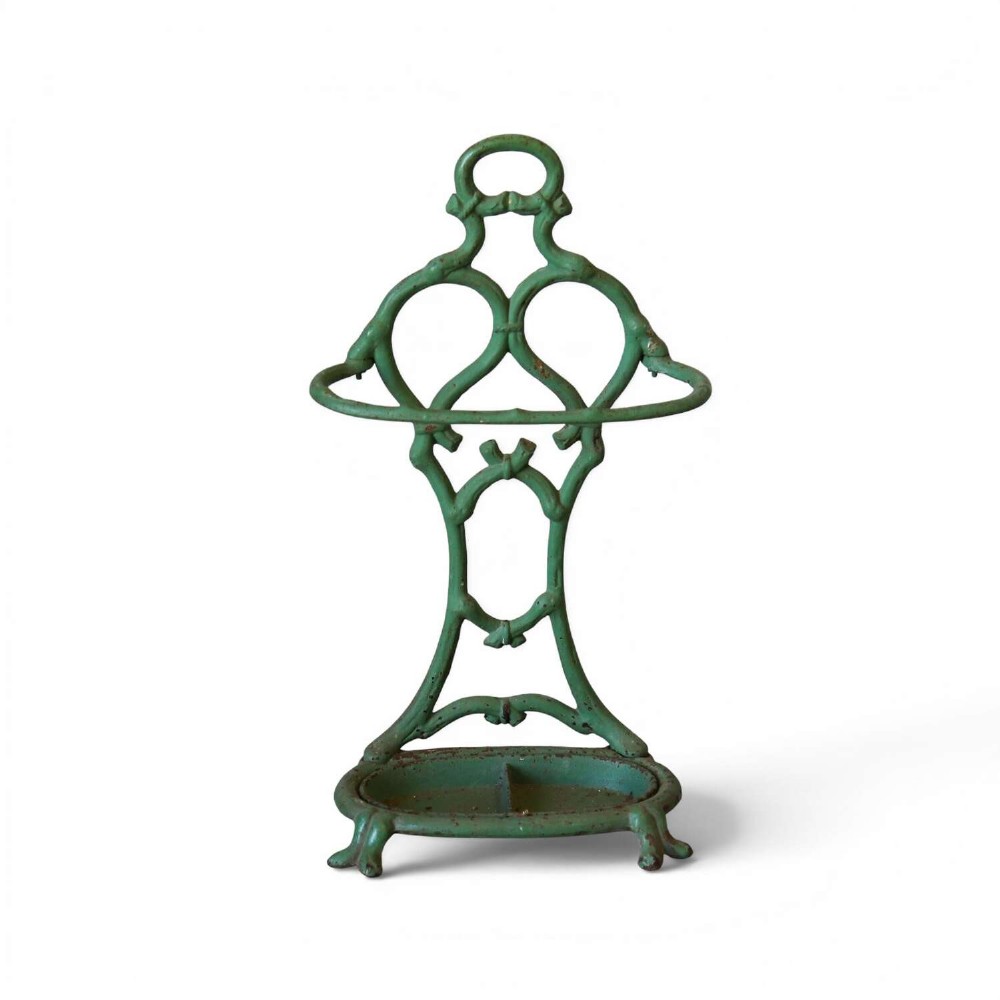 A green painted cast iron umbrella stand featuring a faux bois bamboo framework and an oval drip tray base.