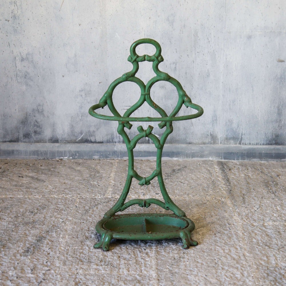 A green painted cast iron umbrella stand featuring a faux bois bamboo framework and an oval drip tray base. View II
