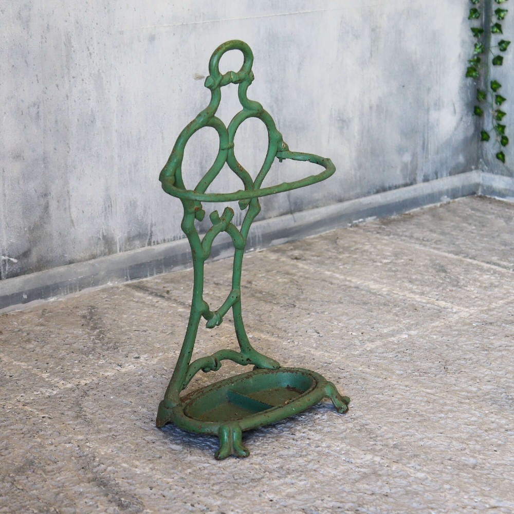 A green painted cast iron umbrella stand featuring a faux bois bamboo framework and an oval drip tray base. View IV