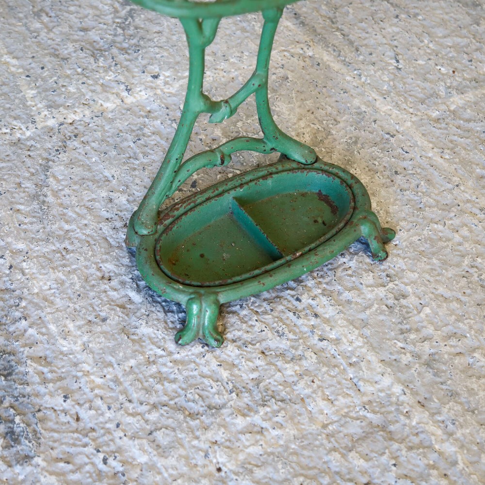 A green painted cast iron umbrella stand featuring a faux bois bamboo framework and an oval drip tray base. View V