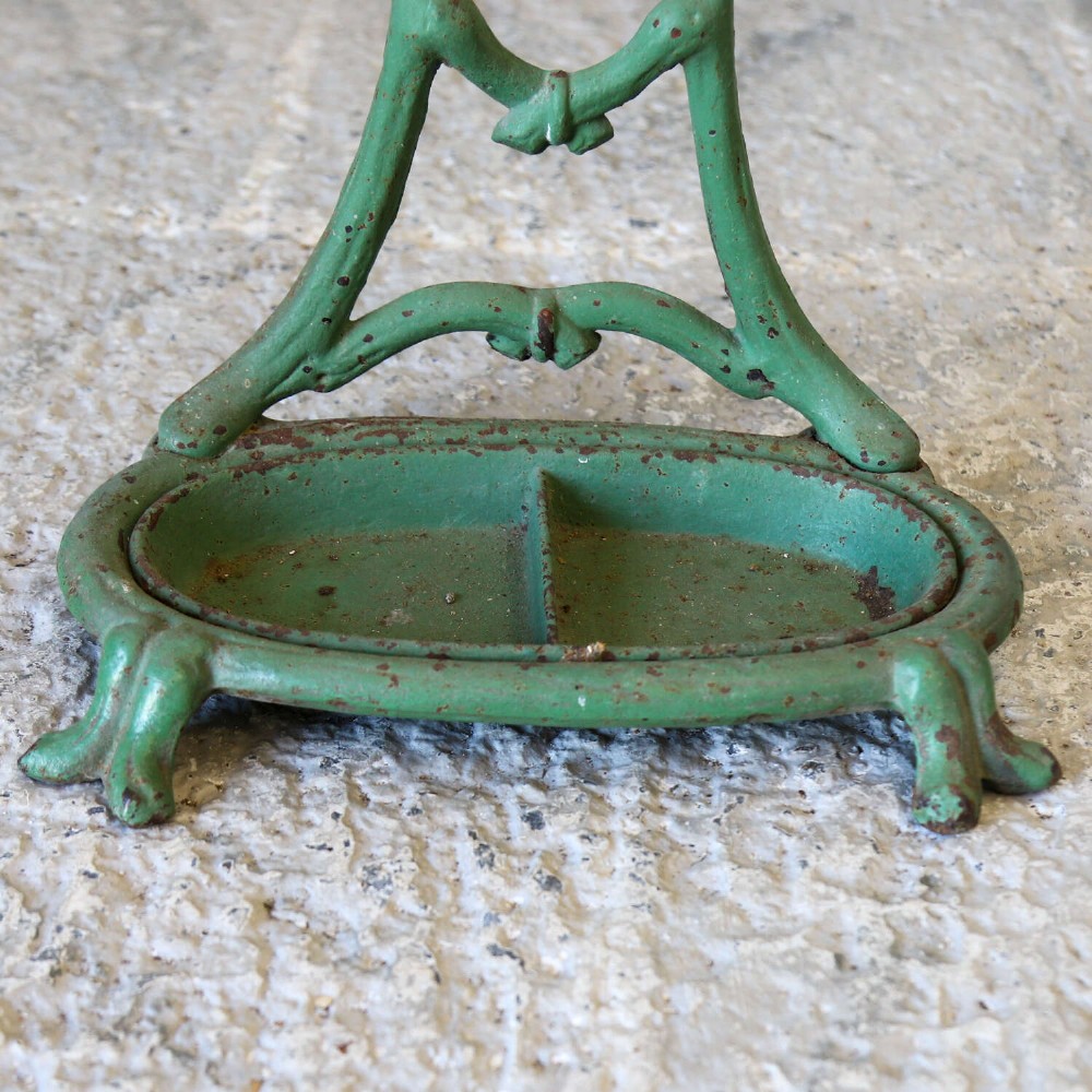 A green painted cast iron umbrella stand featuring a faux bois bamboo framework and an oval drip tray base. View VI
