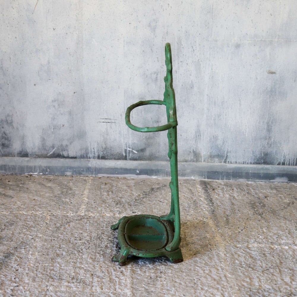 A green painted cast iron umbrella stand featuring a faux bois bamboo framework and an oval drip tray base. View IX