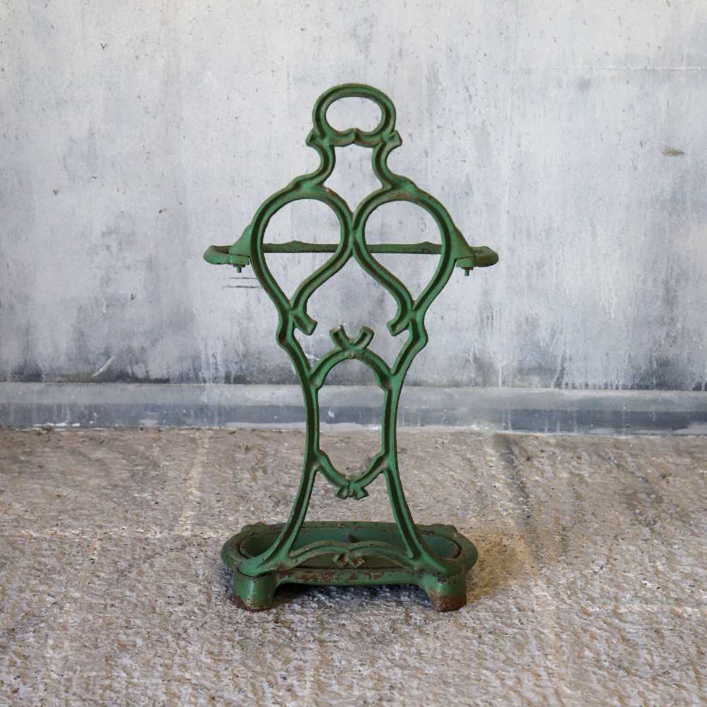 A green painted cast iron umbrella stand featuring a faux bois bamboo framework and an oval drip tray base. View X