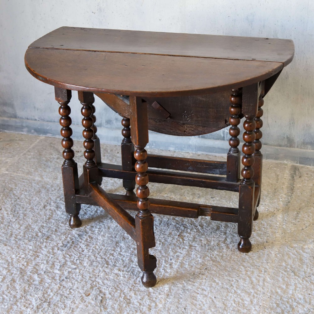 A dark oak gateleg table featuring two hinged drop leaves, bobbin turned legs, and lower box stretchers. View VIII