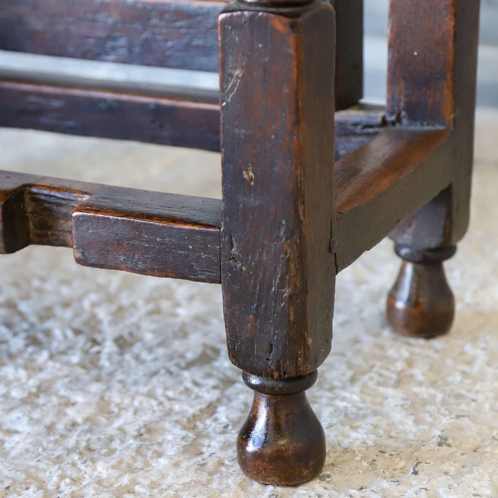 A dark oak gateleg table featuring two hinged drop leaves, bobbin turned legs, and lower box stretchers. View X