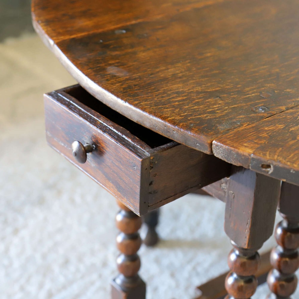 A dark oak gateleg table featuring two hinged drop leaves, bobbin turned legs, and lower box stretchers. View XII