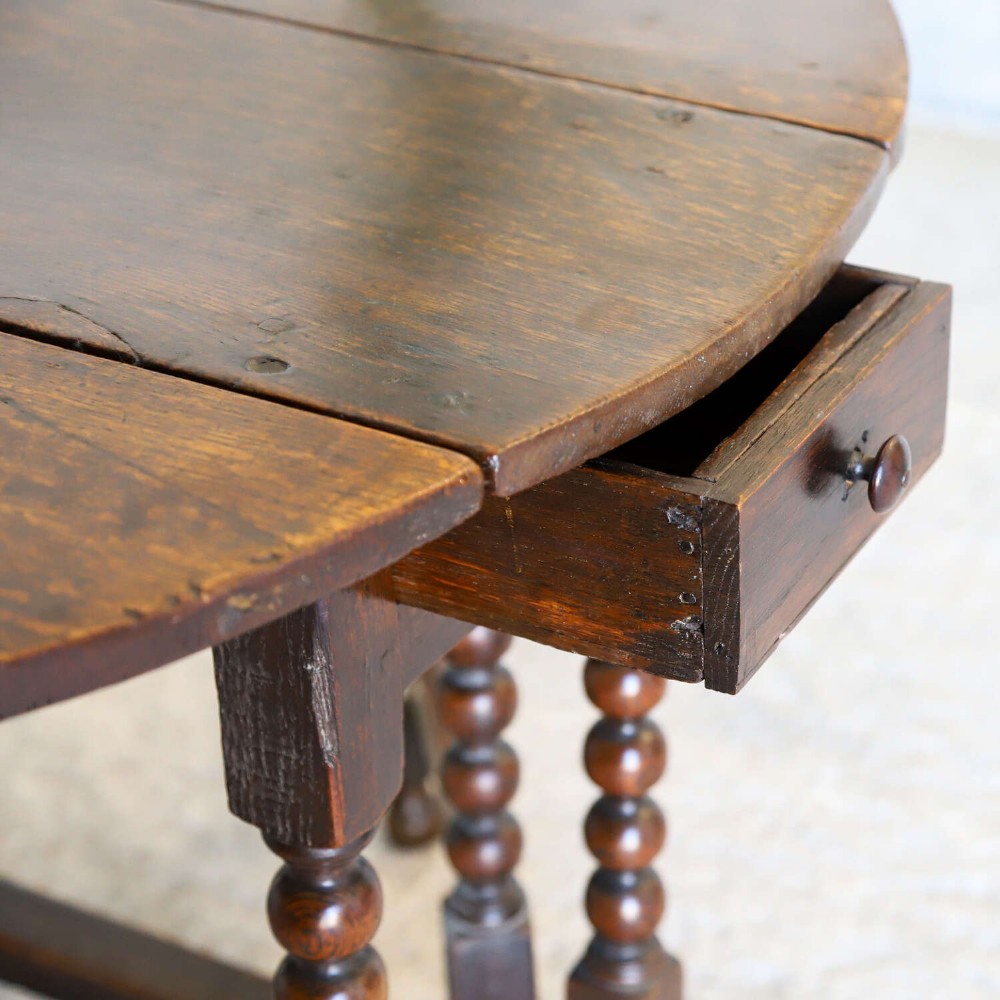 A dark oak gateleg table featuring two hinged drop leaves, bobbin turned legs, and lower box stretchers. View XIII