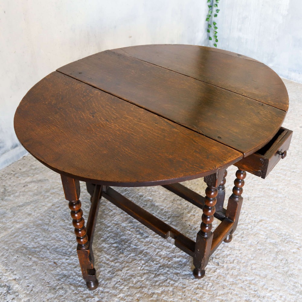 A dark oak gateleg table featuring two hinged drop leaves, bobbin turned legs, and lower box stretchers. View XIV