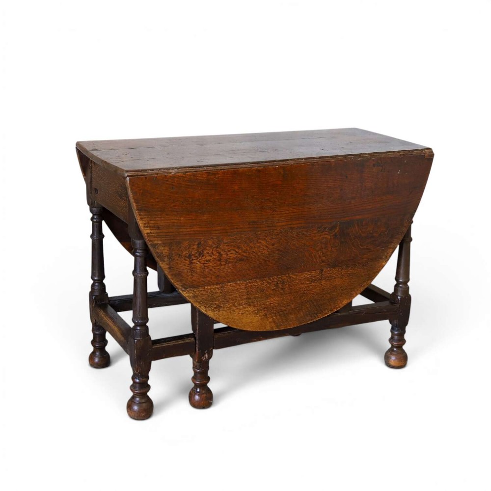 An eighteenth-century oak gateleg drop-leaf table featuring turned legs, lower stretchers, and hinged folding sides.