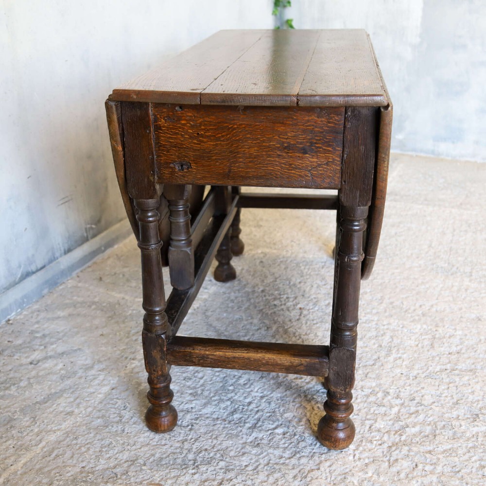 An eighteenth-century oak gateleg drop-leaf table featuring turned legs, lower stretchers, and hinged folding sides. View V