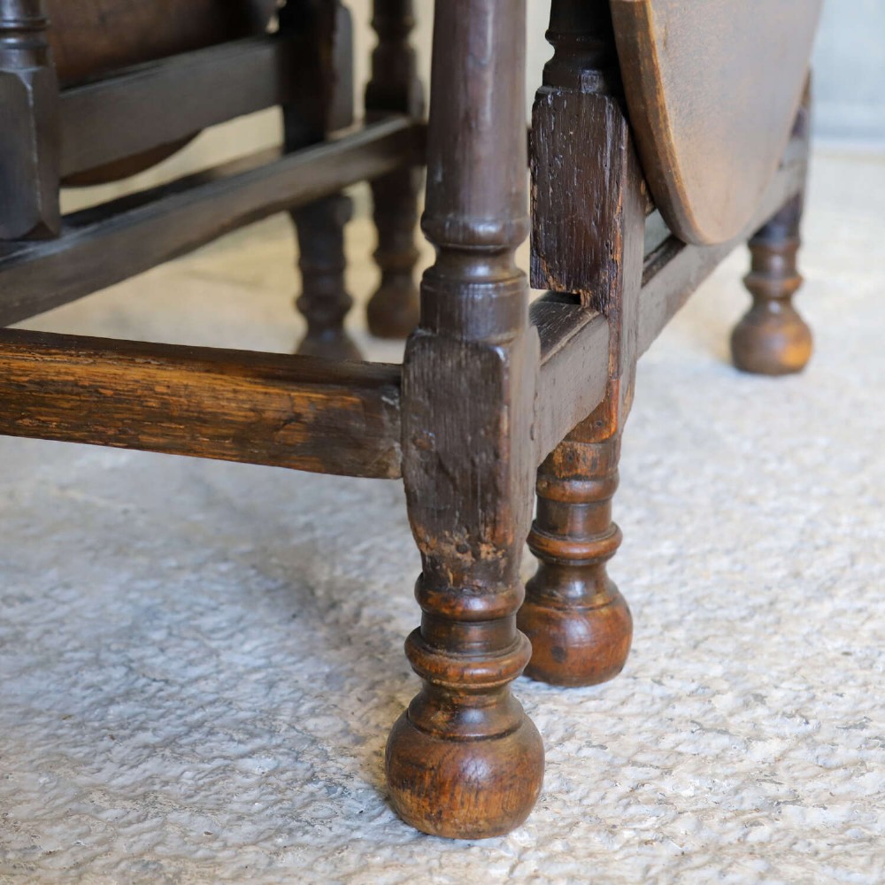 An eighteenth-century oak gateleg drop-leaf table featuring turned legs, lower stretchers, and hinged folding sides. View VII
