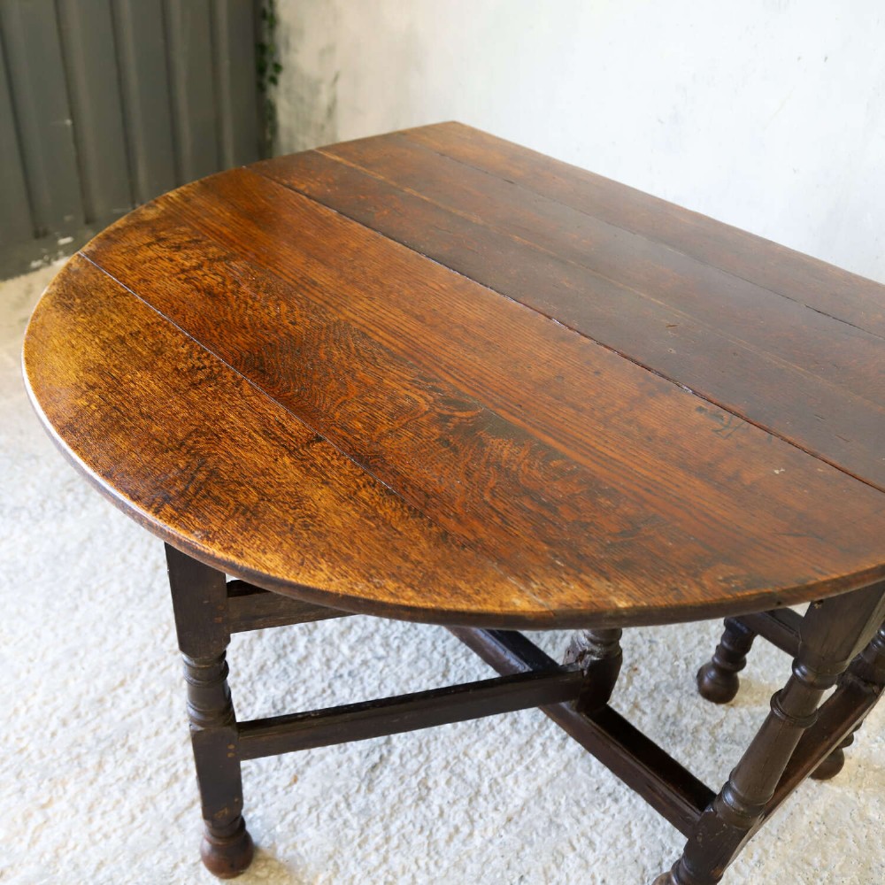 An eighteenth-century oak gateleg drop-leaf table featuring turned legs, lower stretchers, and hinged folding sides. View IX