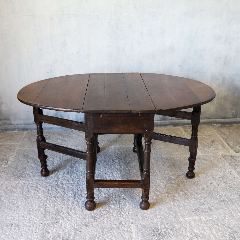An eighteenth-century oak gateleg drop-leaf table featuring turned legs, lower stretchers, and hinged folding sides. View X