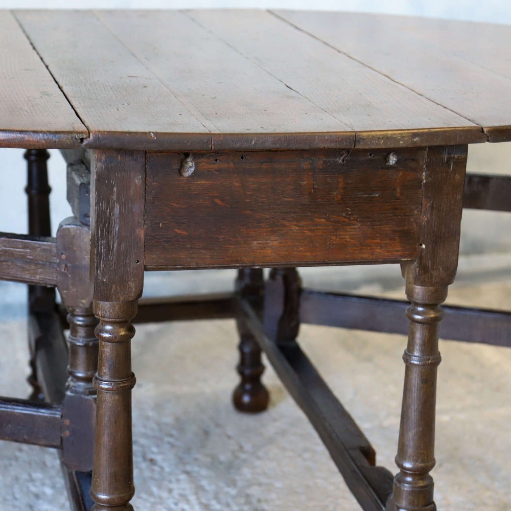An eighteenth-century oak gateleg drop-leaf table featuring turned legs, lower stretchers, and hinged folding sides. View XII