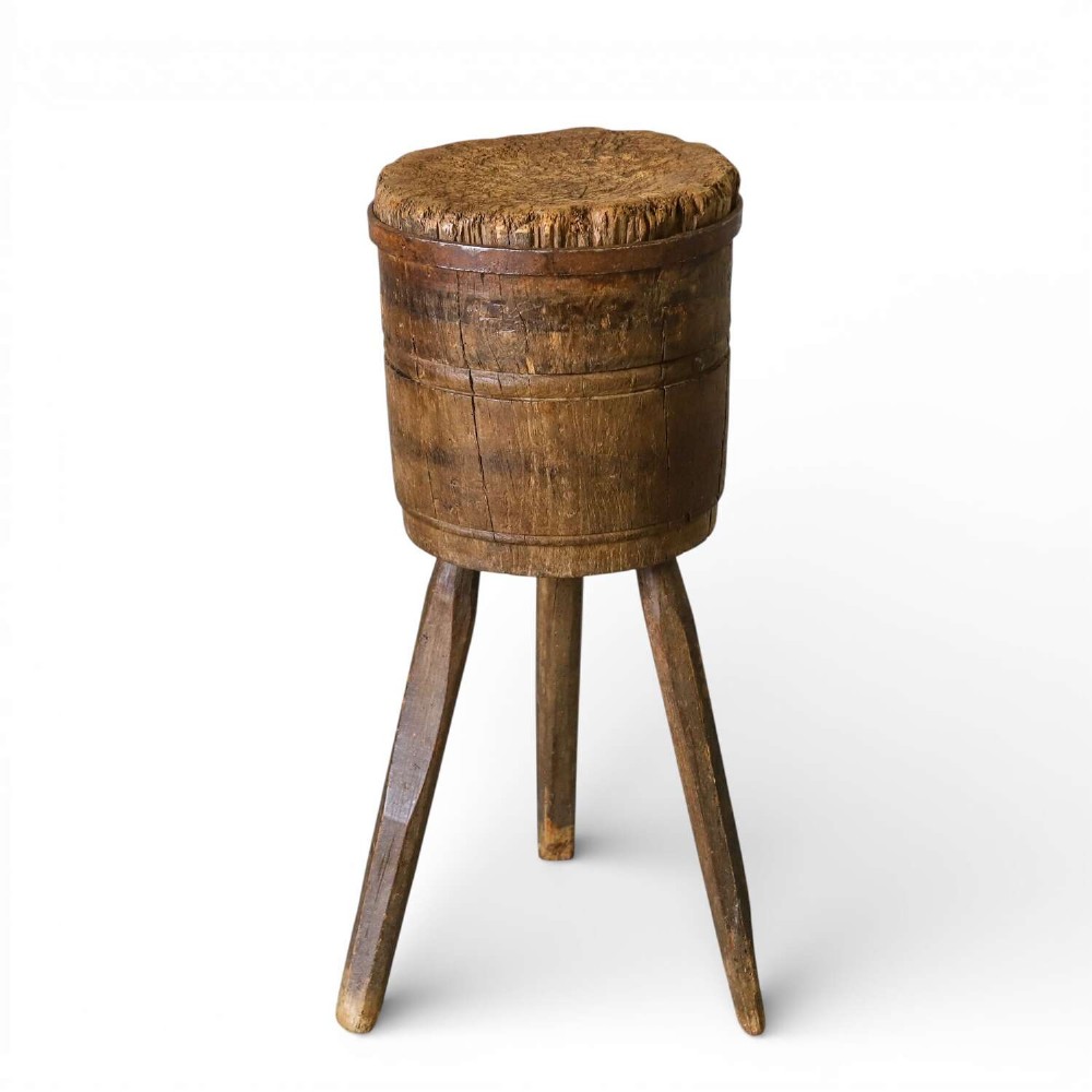A rustic three-legged French chopping block made from oak and elm with a textured wooden top.