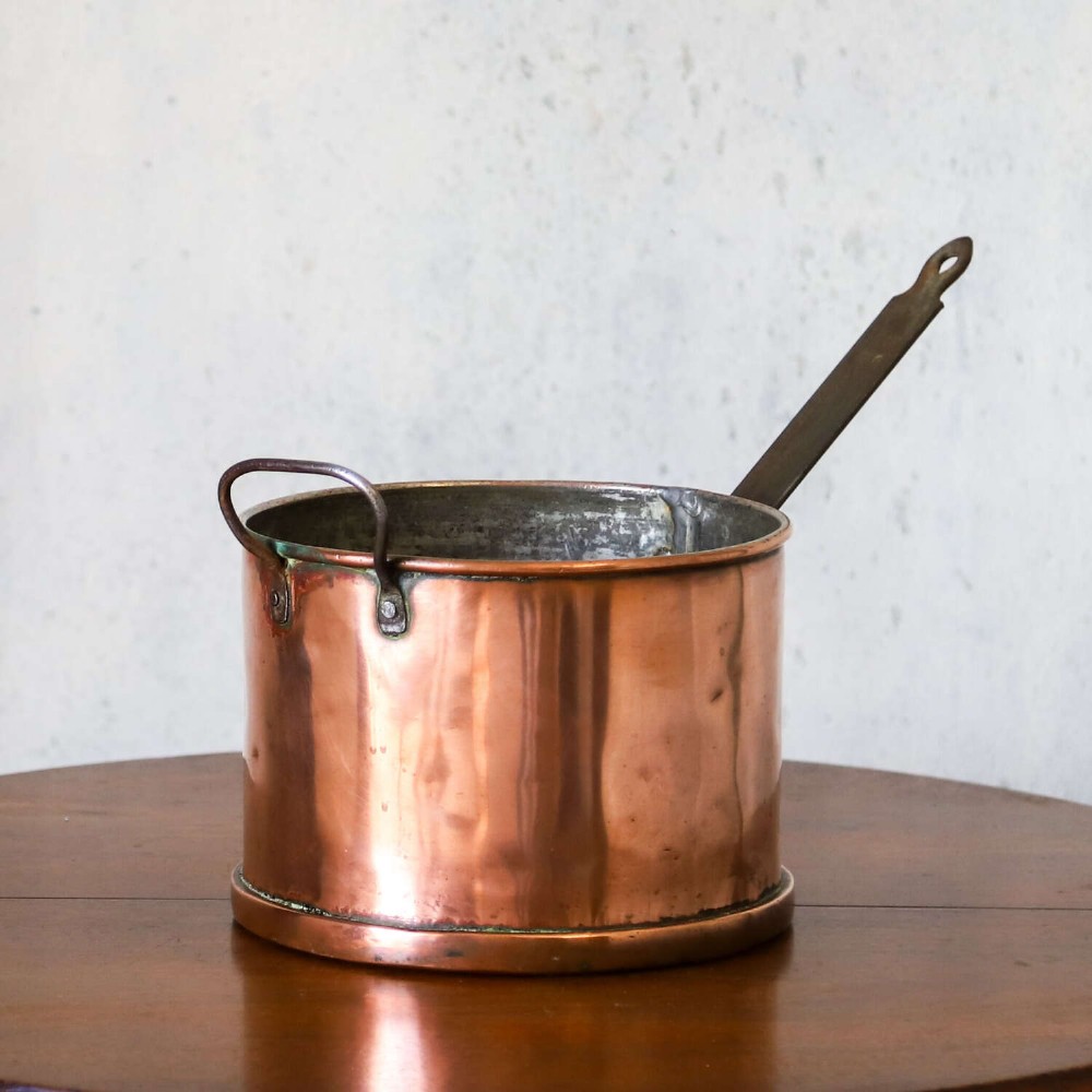 A mid-19th century hand-beaten heavy gauge copper saucepan featuring a long flat iron handle, a side loop handle, and a tinned interior. View III