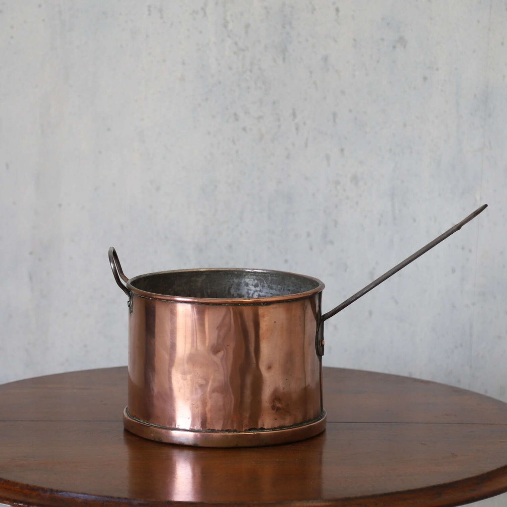A mid-19th century hand-beaten heavy gauge copper saucepan featuring a long flat iron handle, a side loop handle, and a tinned interior. View IV