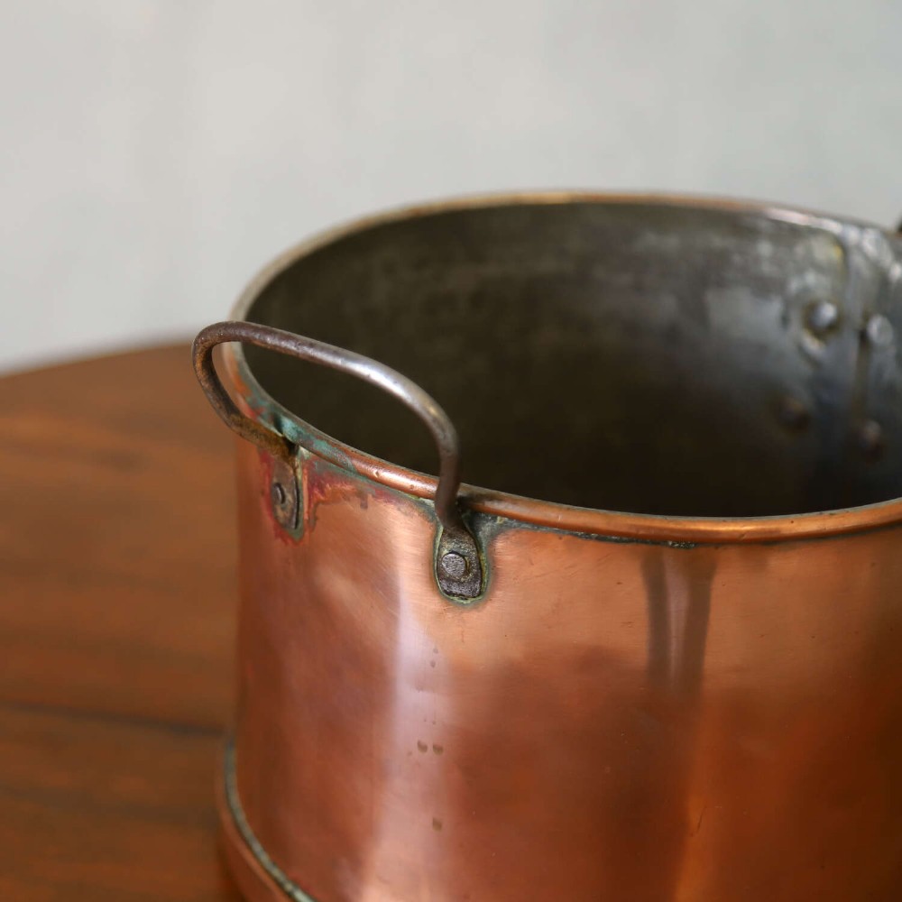 A mid-19th century hand-beaten heavy gauge copper saucepan featuring a long flat iron handle, a side loop handle, and a tinned interior. View V