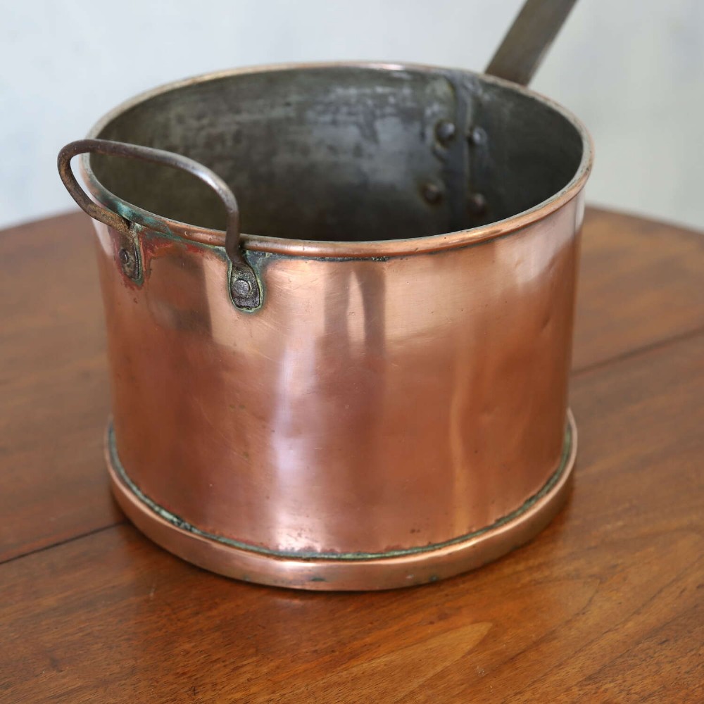A mid-19th century hand-beaten heavy gauge copper saucepan featuring a long flat iron handle, a side loop handle, and a tinned interior. View VII
