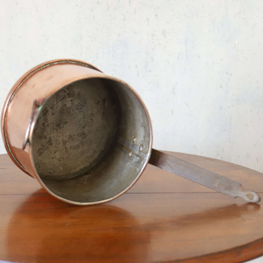 A mid-19th century hand-beaten heavy gauge copper saucepan featuring a long flat iron handle, a side loop handle, and a tinned interior. View VIII