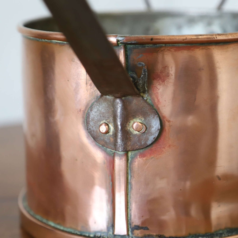 A mid-19th century hand-beaten heavy gauge copper saucepan featuring a long flat iron handle, a side loop handle, and a tinned interior. View X