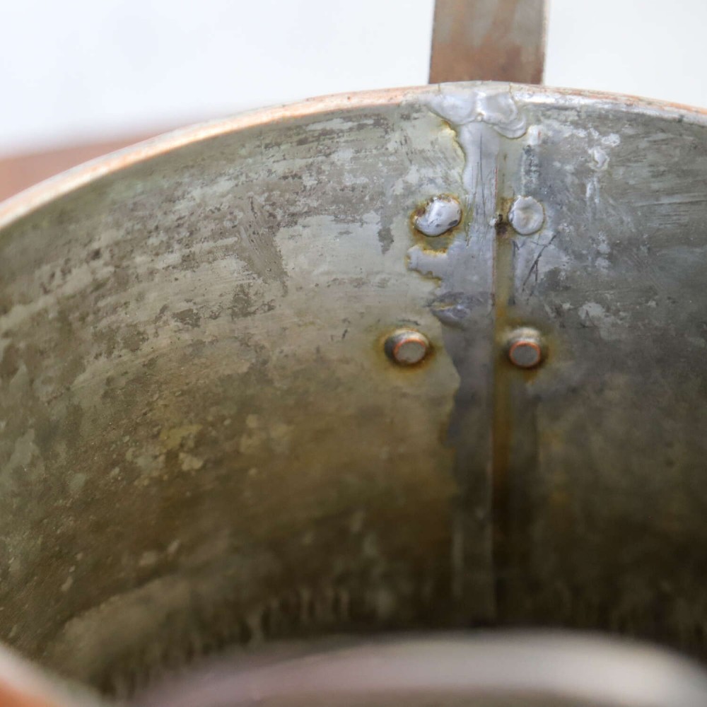 A mid-19th century hand-beaten heavy gauge copper saucepan featuring a long flat iron handle, a side loop handle, and a tinned interior. View XI