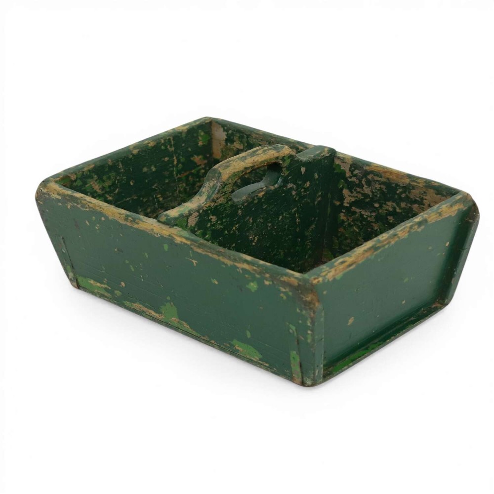 A rectangular dark green painted wooden caddy with a central carrying handle and two compartments, displaying worn paint along the edges.