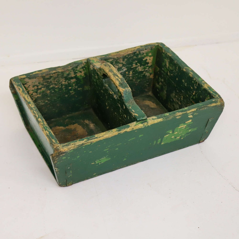 A rectangular dark green painted wooden caddy with a central carrying handle and two compartments, displaying worn paint along the edges. View II