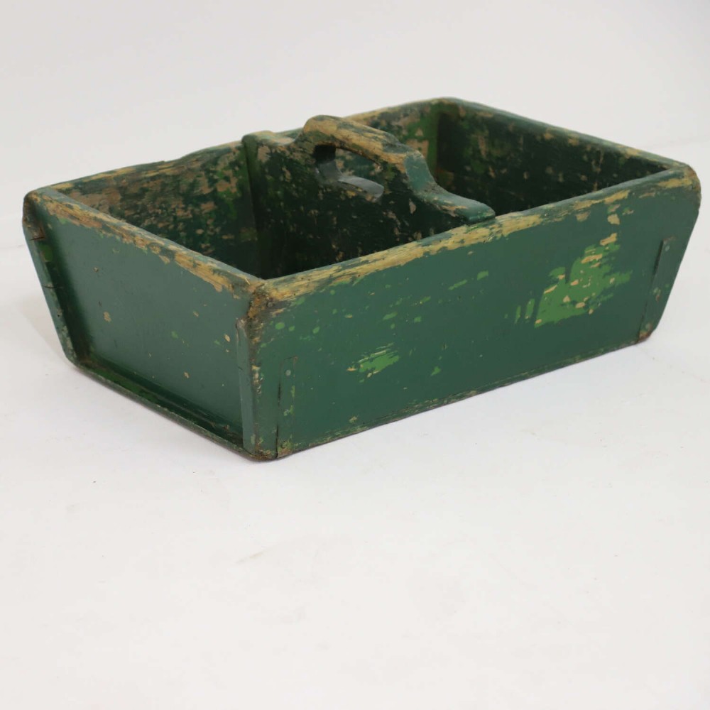 A rectangular dark green painted wooden caddy with a central carrying handle and two compartments, displaying worn paint along the edges. View III