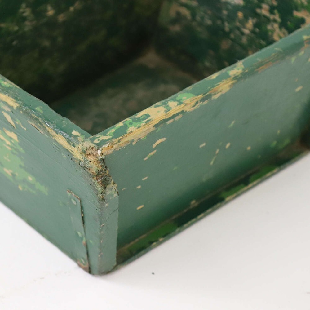 A rectangular dark green painted wooden caddy with a central carrying handle and two compartments, displaying worn paint along the edges. View V