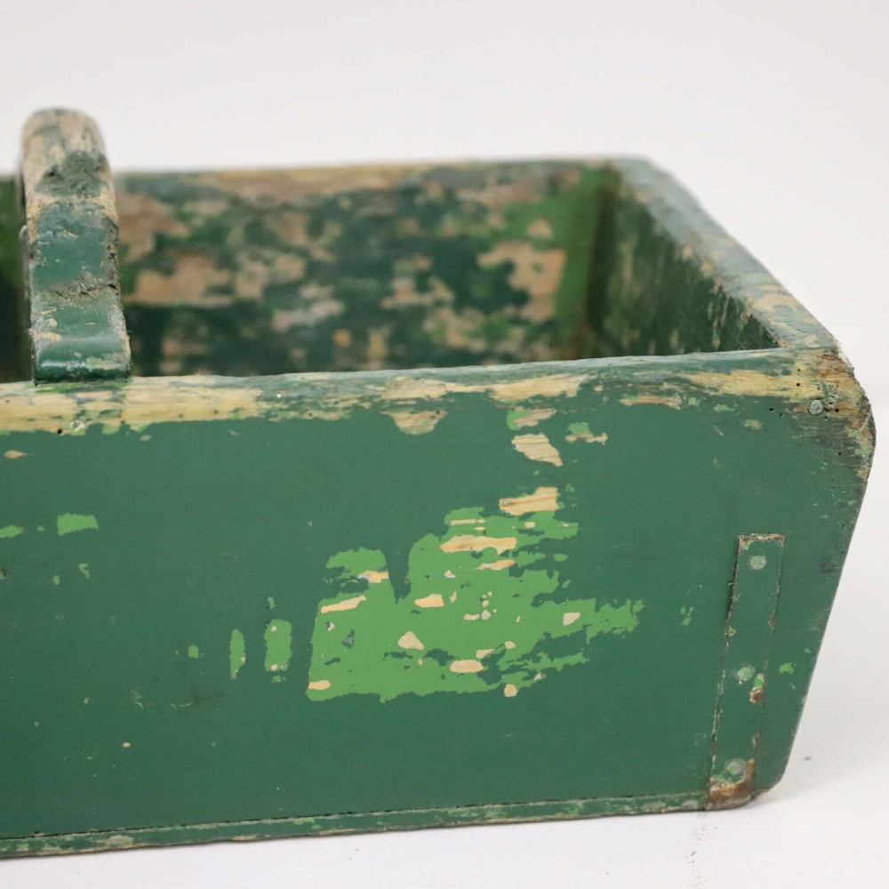 A rectangular dark green painted wooden caddy with a central carrying handle and two compartments, displaying worn paint along the edges. View VI