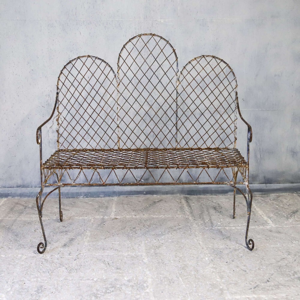 A French Gothic-influenced metal garden bench featuring a triple arched wirework backrest, lattice seat, and scrolled armrests and legs with a weathered, distressed paint finish. View II