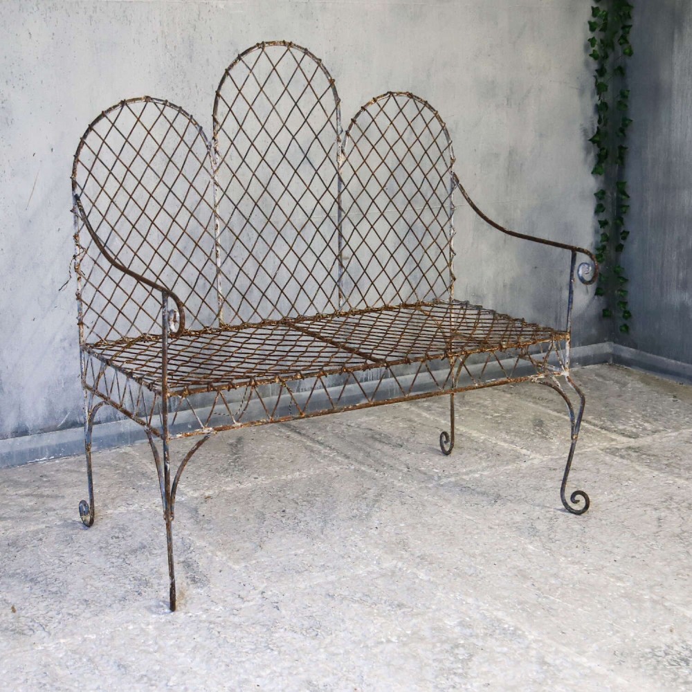 A French Gothic-influenced metal garden bench featuring a triple arched wirework backrest, lattice seat, and scrolled armrests and legs with a weathered, distressed paint finish. View III