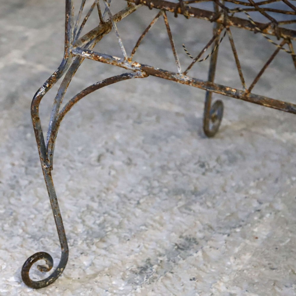 A French Gothic-influenced metal garden bench featuring a triple arched wirework backrest, lattice seat, and scrolled armrests and legs with a weathered, distressed paint finish. View V