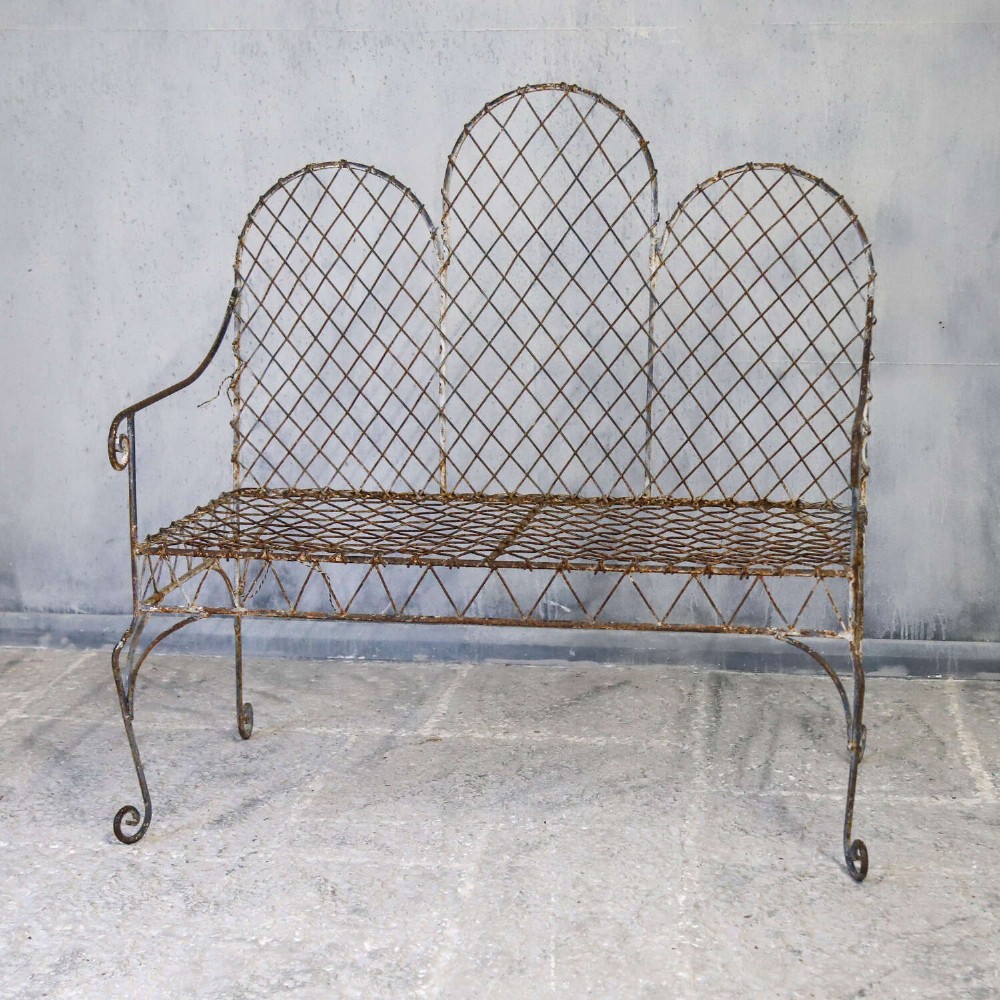 A French Gothic-influenced metal garden bench featuring a triple arched wirework backrest, lattice seat, and scrolled armrests and legs with a weathered, distressed paint finish. View XII