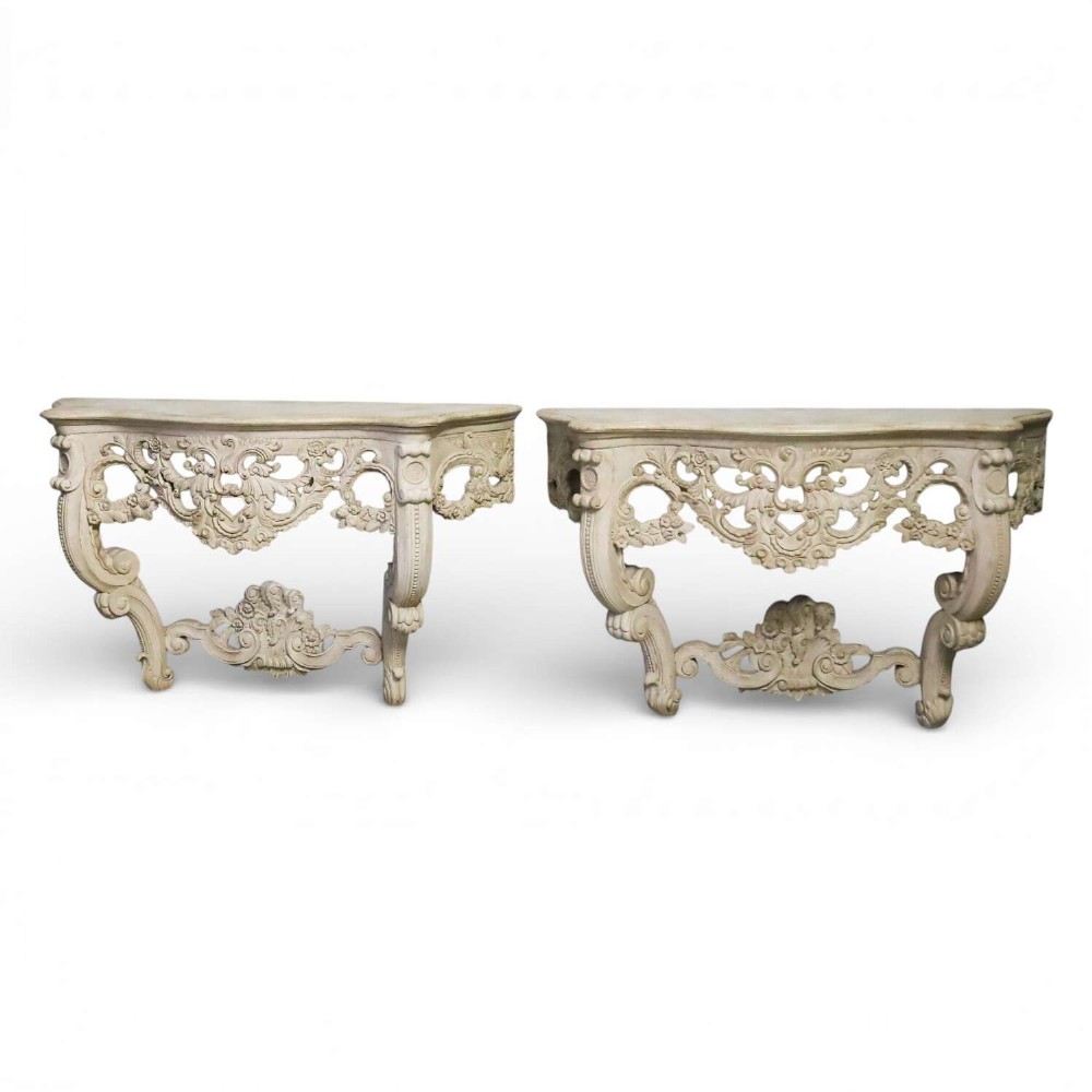 A pair of 1930s French wall console tables with intricate carved Rococo scrollwork in an antique white painted finish. View II