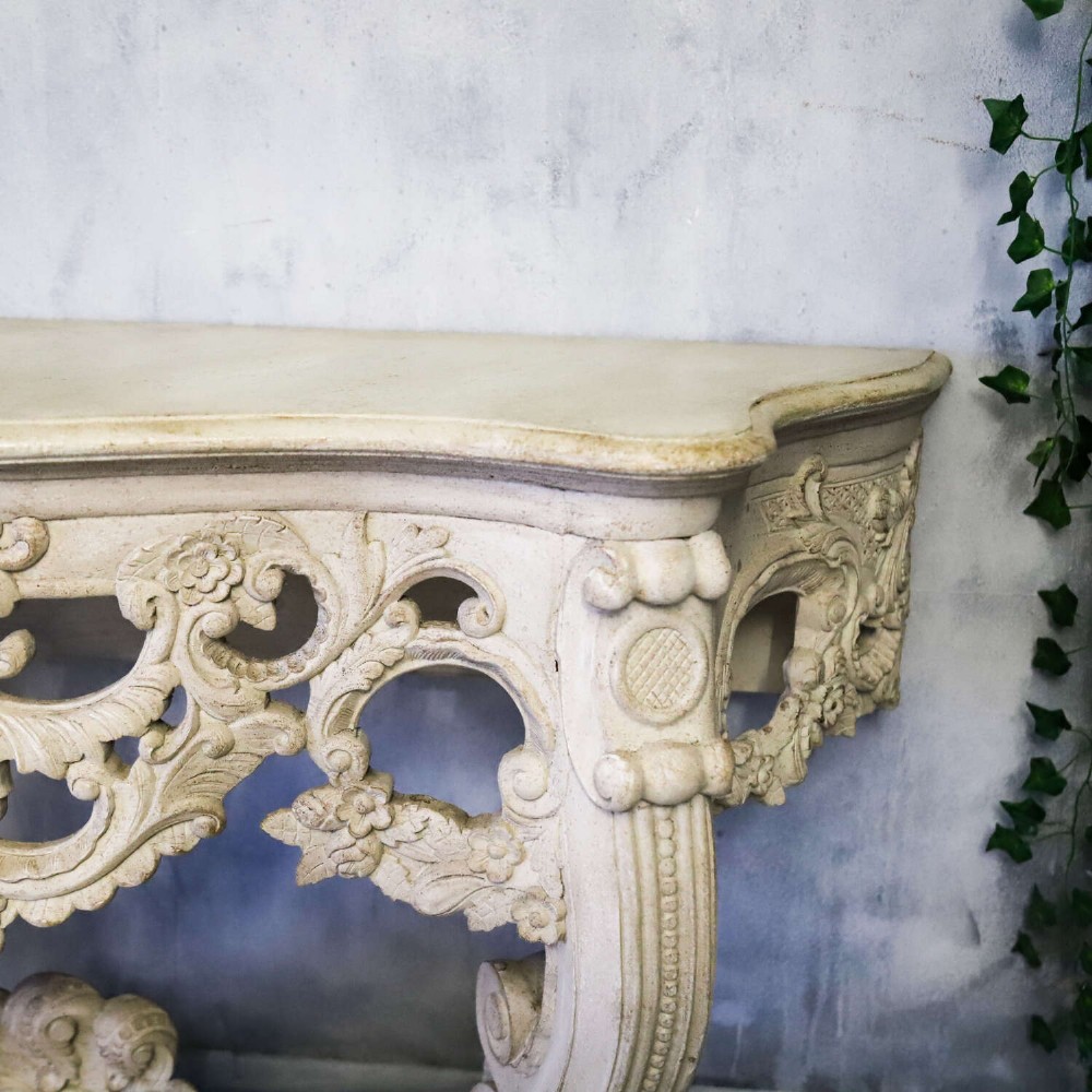 A pair of 1930s French wall console tables with intricate carved Rococo scrollwork in an antique white painted finish. View III