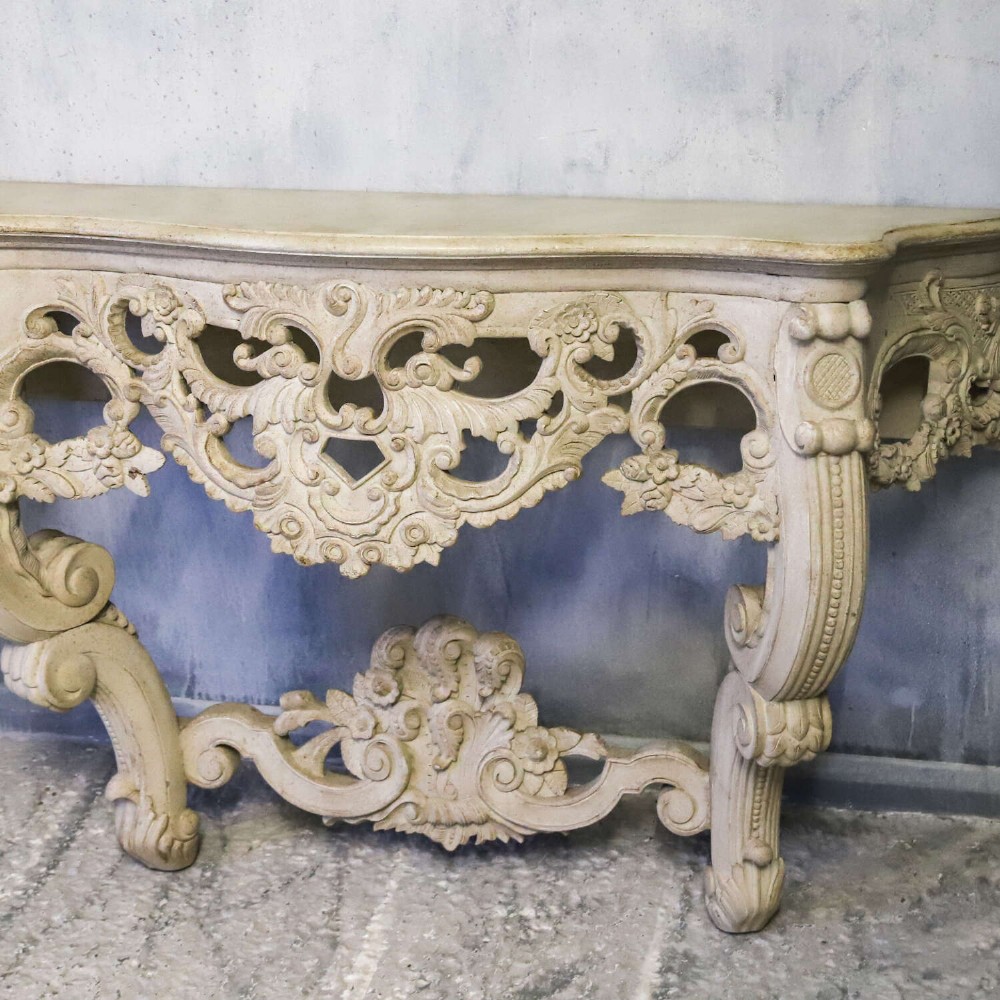 A pair of 1930s French wall console tables with intricate carved Rococo scrollwork in an antique white painted finish. View IV