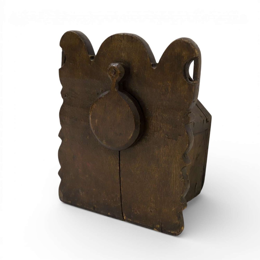 A dark brown 17th or 18th-century carved oak salt box featuring a shaped backboard with a circular hanging aperture and a sloping hinged lid.