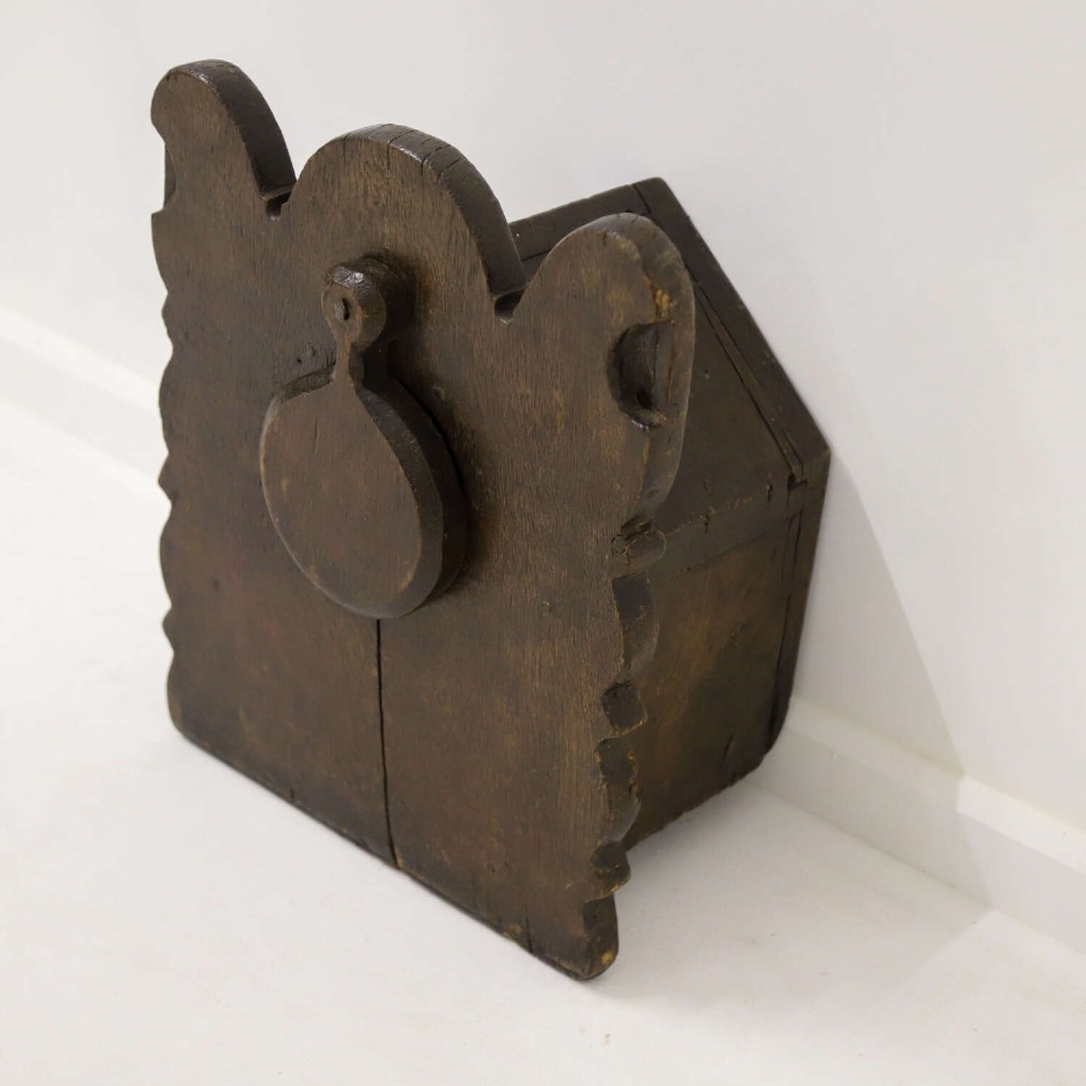 A dark brown 17th or 18th-century carved oak salt box featuring a shaped backboard with a circular hanging aperture and a sloping hinged lid. View III