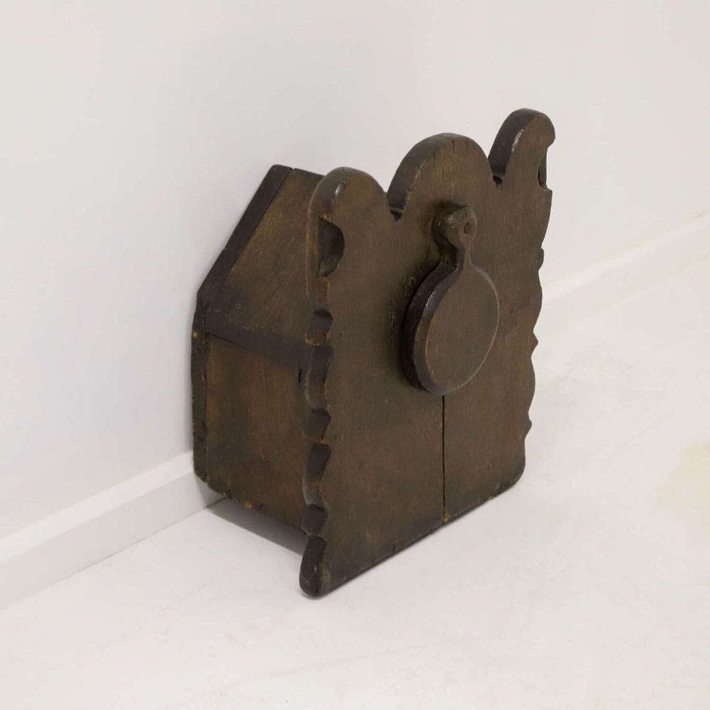 A dark brown 17th or 18th-century carved oak salt box featuring a shaped backboard with a circular hanging aperture and a sloping hinged lid. View IV
